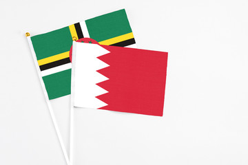 Bahrain and Dominica stick flags on white background. High quality fabric, miniature national flag. Peaceful global concept.White floor for copy space.