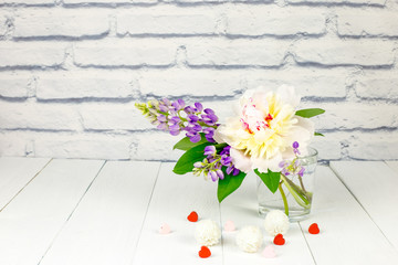 Delicate bouquet with peony and lupines on a white wooden background. Valentine's day card.