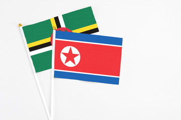 North Korea and Dominica stick flags on white background. High quality fabric, miniature national flag. Peaceful global concept.White floor for copy space.