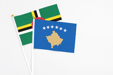 Kosovo and Dominica stick flags on white background. High quality fabric, miniature national flag. Peaceful global concept.White floor for copy space.