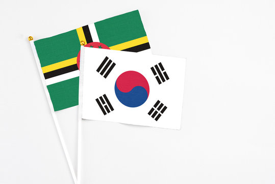 South Korea and Dominica stick flags on white background. High quality fabric, miniature national flag. Peaceful global concept.White floor for copy space.
