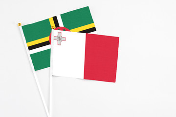 Malta and Dominica stick flags on white background. High quality fabric, miniature national flag. Peaceful global concept.White floor for copy space.