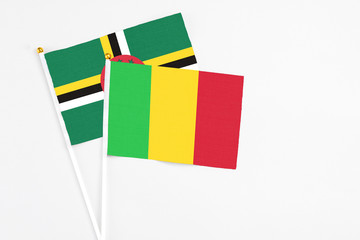 Fototapeta premium Mali and Dominica stick flags on white background. High quality fabric, miniature national flag. Peaceful global concept.White floor for copy space.