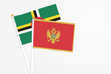 Montenegro and Dominica stick flags on white background. High quality fabric, miniature national flag. Peaceful global concept.White floor for copy space.