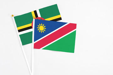 Namibia and Dominica stick flags on white background. High quality fabric, miniature national flag. Peaceful global concept.White floor for copy space.