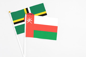 Oman and Dominica stick flags on white background. High quality fabric, miniature national flag. Peaceful global concept.White floor for copy space.