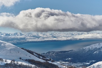Paisaje de un lago desde una montaña donde las nubes están en primer plano