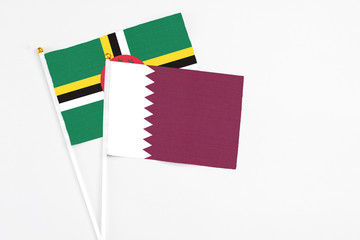 Qatar and Dominica stick flags on white background. High quality fabric, miniature national flag. Peaceful global concept.White floor for copy space.