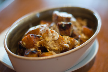 SPICED ROASTED PUMPKIN with savoury granola and yoghurt in a white porcelain dish