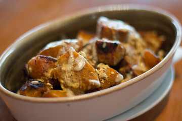 SPICED ROASTED PUMPKIN with savoury granola and yoghurt in a white porcelain dish
