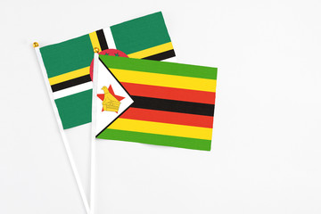 Zimbabwe and Dominica stick flags on white background. High quality fabric, miniature national flag. Peaceful global concept.White floor for copy space.