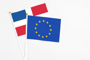 European Union and Dominican Republic stick flags on white background. High quality fabric, miniature national flag. Peaceful global concept.White floor for copy space.