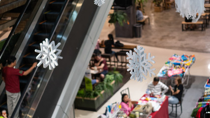 Many snowflake symbols hung beside the stairs in a mall in Thailand.