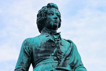 Mozart monument on Mozartplatz Square at Old city of Salzburg of Austria, Europe at winter. Wolfgang Amadeus Statue. View on Sculpture in Austrian town of Salzburgerland. Sky with clouds.