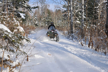 An ATV on wheels ride on a taiga forest road in winter