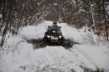 An ATV on wheels ride on a taiga forest road in winter