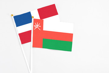 Oman and Dominican Republic stick flags on white background. High quality fabric, miniature national flag. Peaceful global concept.White floor for copy space.