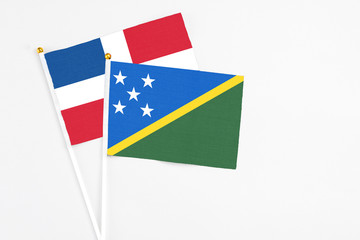 Solomon Islands and Dominican Republic stick flags on white background. High quality fabric, miniature national flag. Peaceful global concept.White floor for copy space.