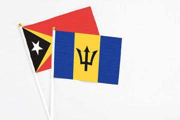Barbados and East Timor stick flags on white background. High quality fabric, miniature national flag. Peaceful global concept.White floor for copy space.