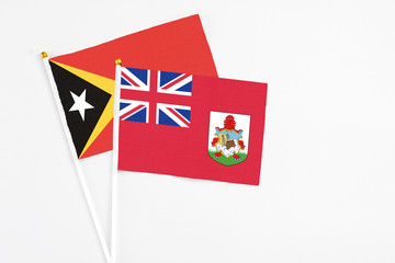 Bermuda and East Timor stick flags on white background. High quality fabric, miniature national flag. Peaceful global concept.White floor for copy space.