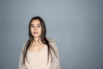 the frightened face of a beautiful dark-haired girl on a dark blue background shows the emotion of fear on her face