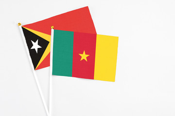 Cameroon and East Timor stick flags on white background. High quality fabric, miniature national flag. Peaceful global concept.White floor for copy space.