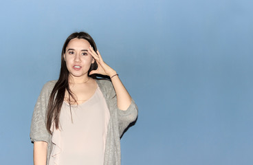 confident black-haired girl in a white blouse and a gray blouse with emotion on her face leaned her hand to her head