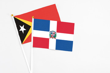 Dominican Republic and East Timor stick flags on white background. High quality fabric, miniature national flag. Peaceful global concept.White floor for copy space.