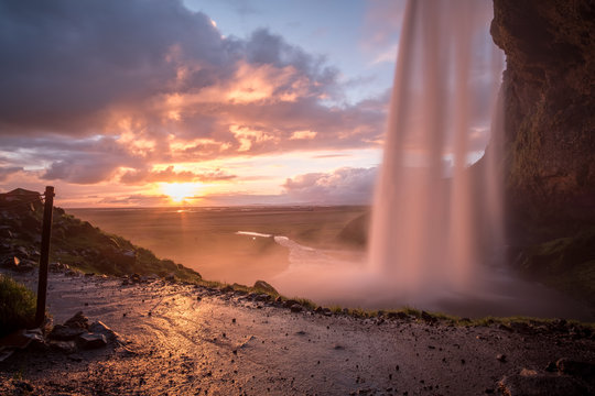 Picturesque sunset photo taken from within Seljalandsfoss water in Iceland