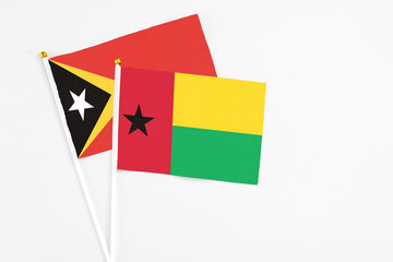 Guinea Bissau and East Timor stick flags on white background. High quality fabric, miniature national flag. Peaceful global concept.White floor for copy space.