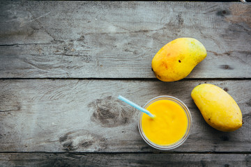 Mango smoothie in glass and mango fruits on wooden table - 302576794