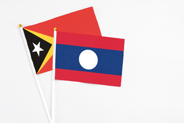 Laos and East Timor stick flags on white background. High quality fabric, miniature national flag. Peaceful global concept.White floor for copy space.