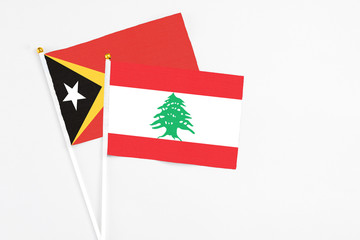 Lebanon and East Timor stick flags on white background. High quality fabric, miniature national flag. Peaceful global concept.White floor for copy space.