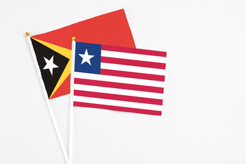 Liberia and East Timor stick flags on white background. High quality fabric, miniature national flag. Peaceful global concept.White floor for copy space.