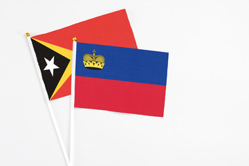 Liechtenstein and East Timor stick flags on white background. High quality fabric, miniature national flag. Peaceful global concept.White floor for copy space.