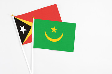 Mauritania and East Timor stick flags on white background. High quality fabric, miniature national flag. Peaceful global concept.White floor for copy space.