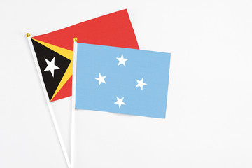 Micronesia and East Timor stick flags on white background. High quality fabric, miniature national flag. Peaceful global concept.White floor for copy space.