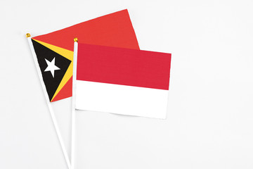 Monaco and East Timor stick flags on white background. High quality fabric, miniature national flag. Peaceful global concept.White floor for copy space.