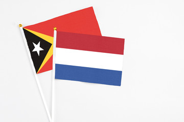 Netherlands and East Timor stick flags on white background. High quality fabric, miniature national flag. Peaceful global concept.White floor for copy space.