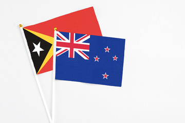 Fototapeta premium New Zealand and East Timor stick flags on white background. High quality fabric, miniature national flag. Peaceful global concept.White floor for copy space.