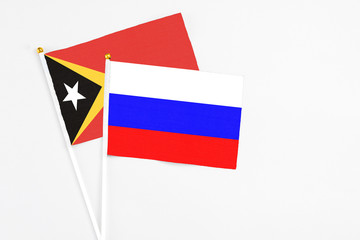 Russia and East Timor stick flags on white background. High quality fabric, miniature national flag. Peaceful global concept.White floor for copy space.