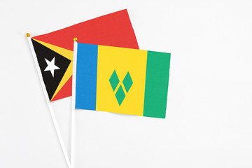 Saint Vincent And The Grenadines and East Timor stick flags on white background. High quality fabric, miniature national flag. Peaceful global concept.White floor for copy space.