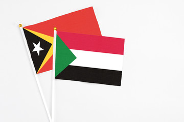 Sudan and East Timor stick flags on white background. High quality fabric, miniature national flag. Peaceful global concept.White floor for copy space.