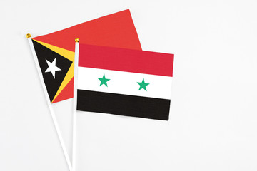 Syria and East Timor stick flags on white background. High quality fabric, miniature national flag. Peaceful global concept.White floor for copy space.