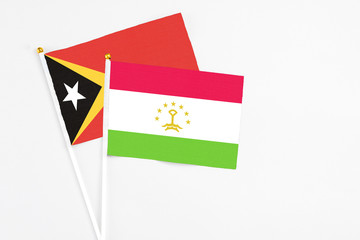 Tajikistan and East Timor stick flags on white background. High quality fabric, miniature national flag. Peaceful global concept.White floor for copy space.