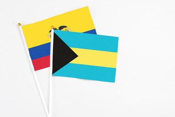 Bahamas and Ecuador stick flags on white background. High quality fabric, miniature national flag. Peaceful global concept.White floor for copy space.