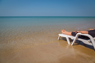 Fototapeta na wymiar Vacation on tropical beach Woman's legs on the beach bed with clear ocean water