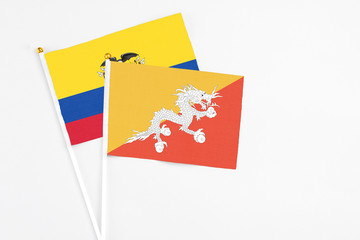 Bhutan and Ecuador stick flags on white background. High quality fabric, miniature national flag. Peaceful global concept.White floor for copy space.