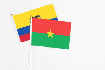 Fototapeta premium Burkina Faso and Ecuador stick flags on white background. High quality fabric, miniature national flag. Peaceful global concept.White floor for copy space.