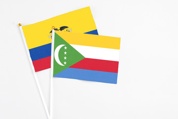Comoros and Ecuador stick flags on white background. High quality fabric, miniature national flag. Peaceful global concept.White floor for copy space.